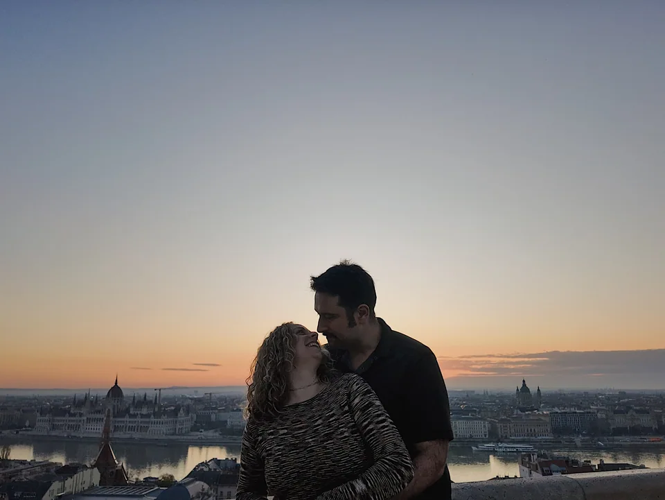 Two people looking at each other above a city skyline at sunset