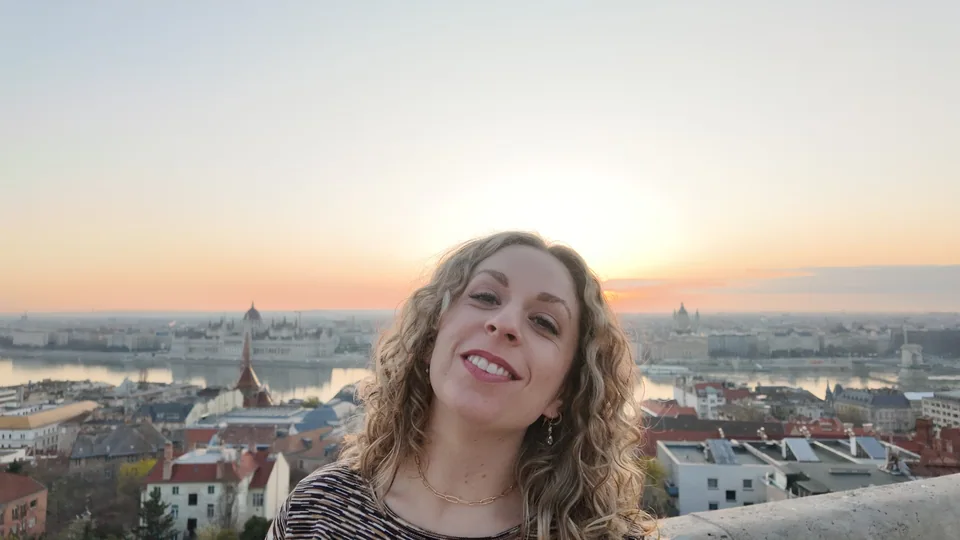A close smiling portrait with a city skyline and sunset behind