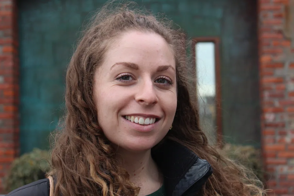 A close outdoor portrait of a smiling person with a softly focused background