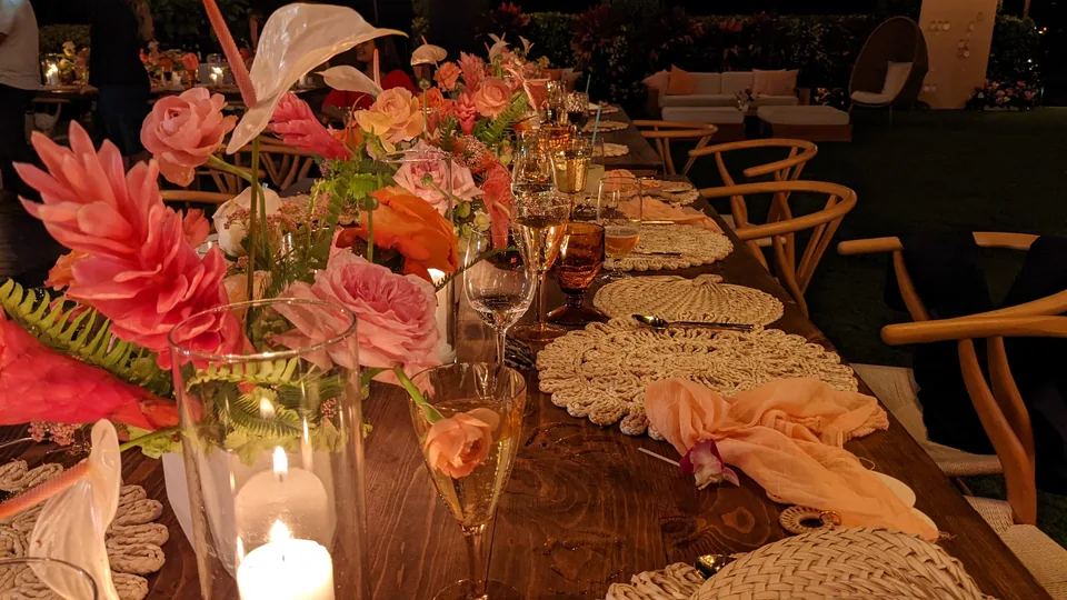 Pink flowers, candles and woven place settings along a reception table